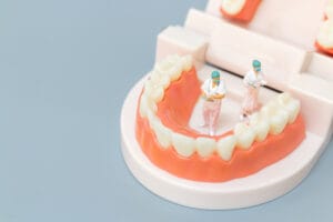 miniature figures standing near a tooth model 2026 03 26 06 16 29 utc